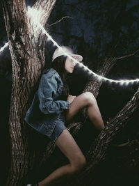 Young woman sitting on tree trunk in forest