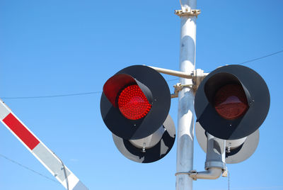 Low angle view of road signal against clear blue sky