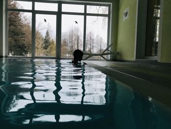 Reflection of man swimming in pool