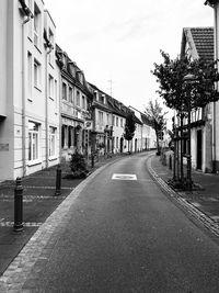 Empty road amidst buildings against sky