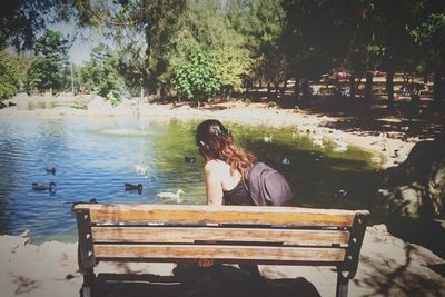 Woman sitting on bench by lake