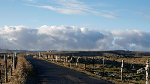 Panoramic shot of road amidst field against sky