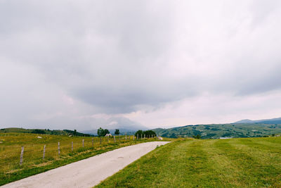 Road amidst field against sky