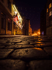 Surface level of illuminated street amidst buildings in city at night