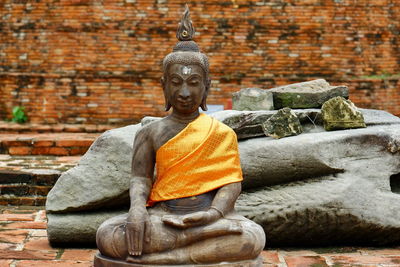 Buddha statue against brick wall