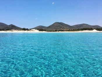 Swimming pool by sea against blue sky