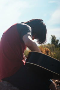 Low section of man sitting against sky