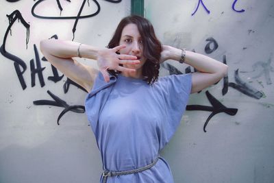 Portrait of young woman standing against graffiti wall