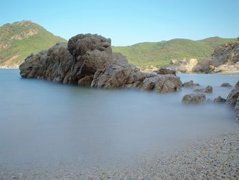 Rocks in sea against clear sky