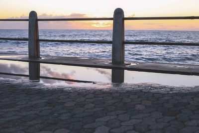 Close-up of railing by sea against sky at sunset