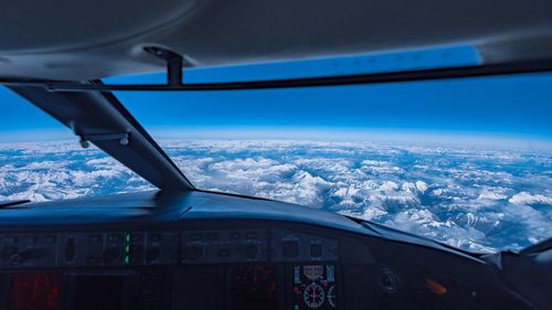 Airplane wing against sky seen through window