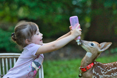 Cute girl feeding deer outdoors