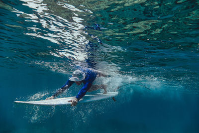 Male surfer diving with surfboard in sea at maldives