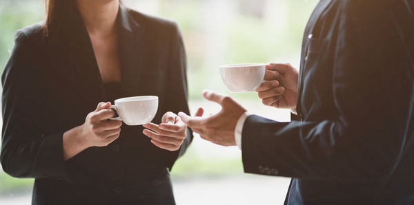 Midsection of friends drinking coffee