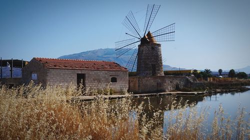 Traditional windmill on landscape against clear sky, saline, trapani