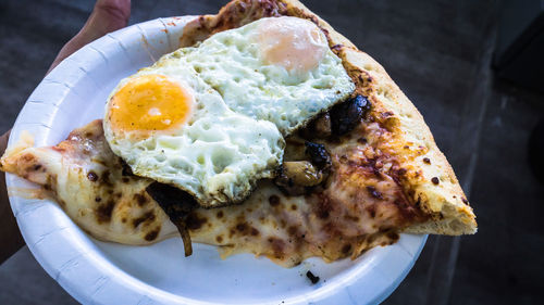 Cropped hand holding plate in food