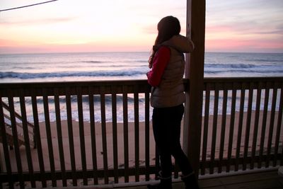 Full length of woman standing on railing against sea