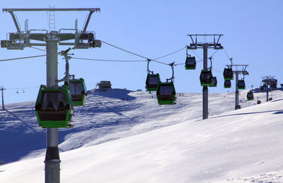 Overhead cable car on snow covered mountain against sky