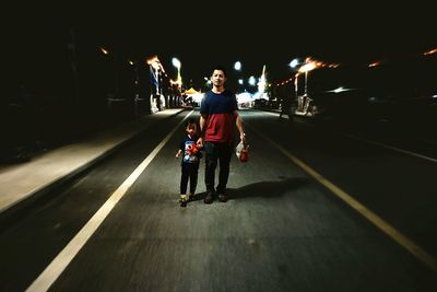 Young woman walking on illuminated street at night