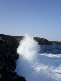 Water splashing on sea against clear sky