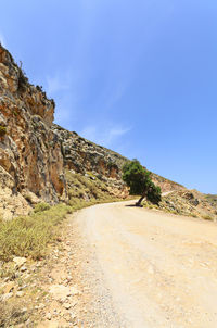 Road by mountain against blue sky