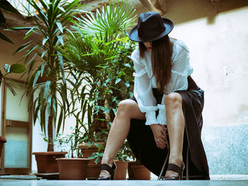 Young woman sitting by plants on stool