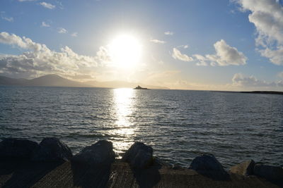 Sun shining through clouds over sea