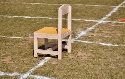Empty chair on field during sunny day