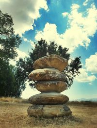 Stack of stone on field against sky