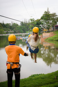 Rear view of man standing by woman hanging from zip line