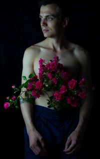 Midsection of shirtless man standing against black background