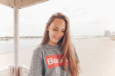 Portrait of smiling young woman standing against sky