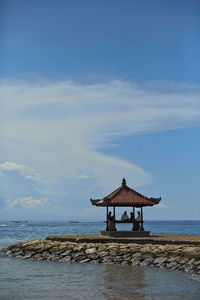 Lifeguard hut by sea against blue sky