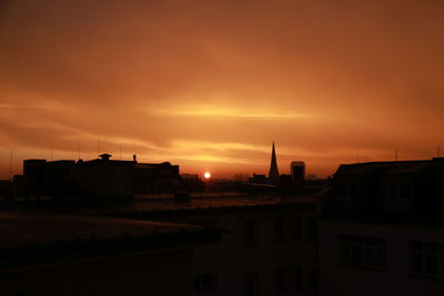 Silhouette buildings in city against sky during sunset