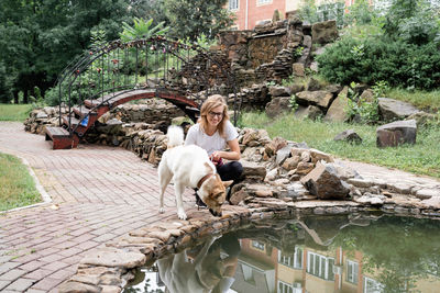 Young caucasian woman walking her dog in a summer park