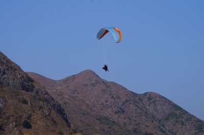 Low angle view of man paragliding against clear sky