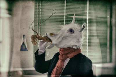 Person in unicorn mask holding toy
