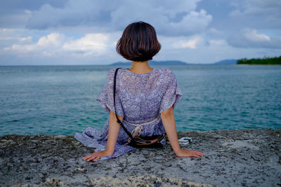 Rear view of woman sitting on sea shore