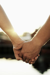 Close-up of couple holding hands at lake