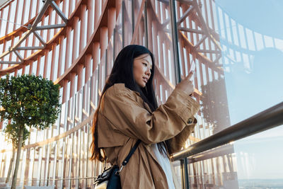 Young woman looking away while standing on railing