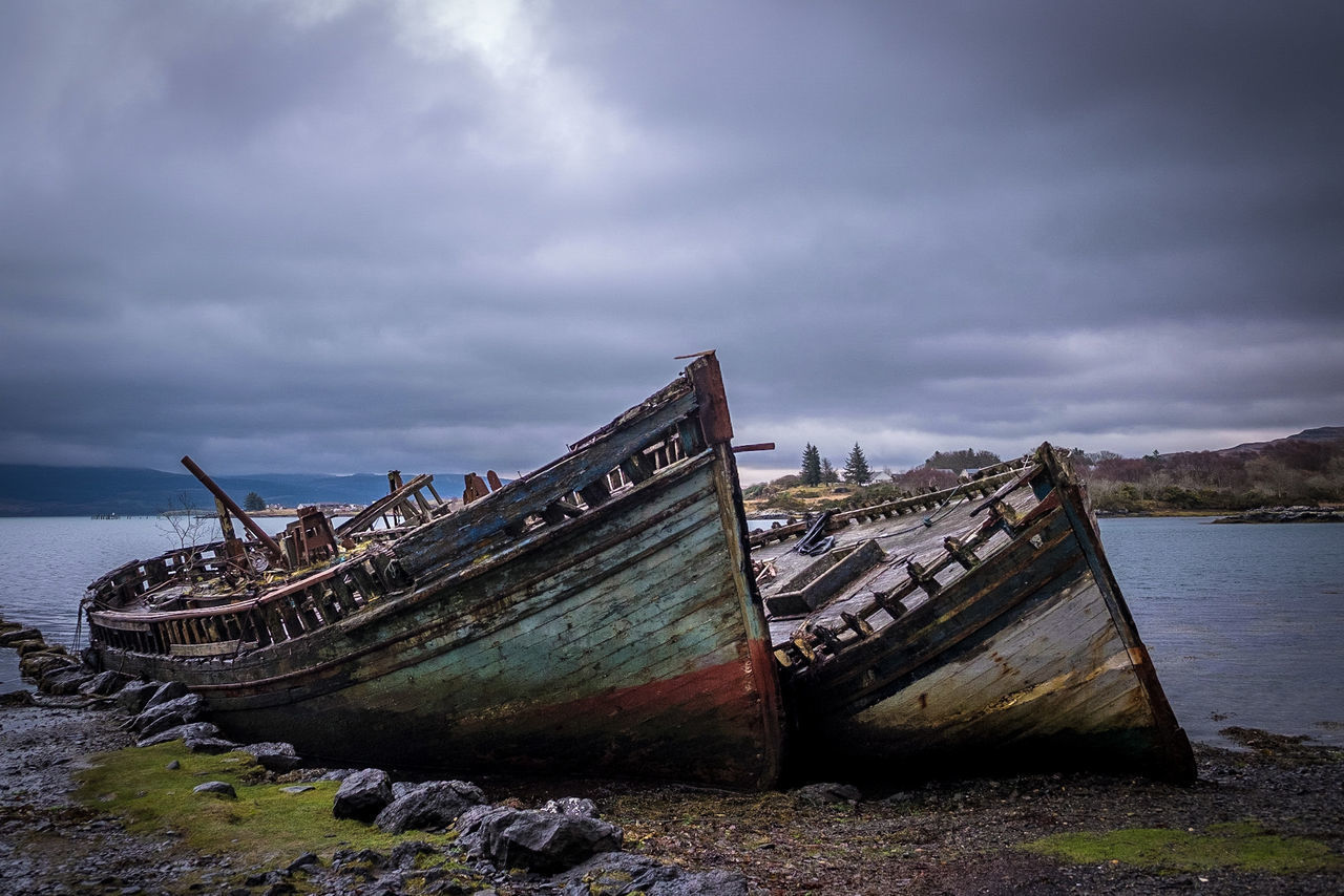 ABANDONED BOAT AT SHORE AGAINST SKY