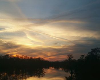 Silhouette trees on landscape against sky at sunset