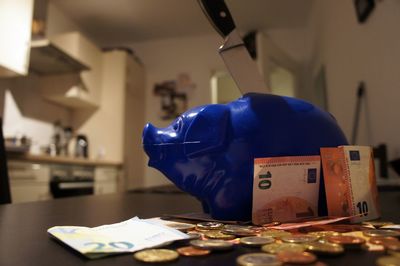 Close up view of money by piggy bank on table at home