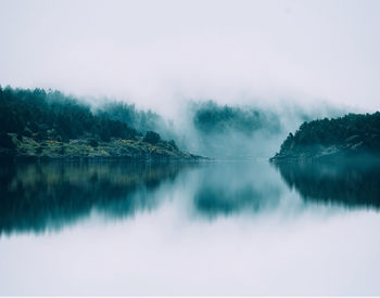 Scenic view of lake against clear sky in foggy weather