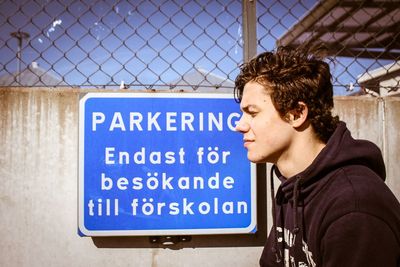 Thoughtful man sitting against information sign on surrounding wall