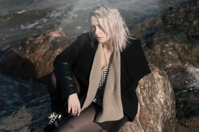 Portrait of woman sitting on rock at beach