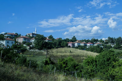 Houses on field by buildings against sky