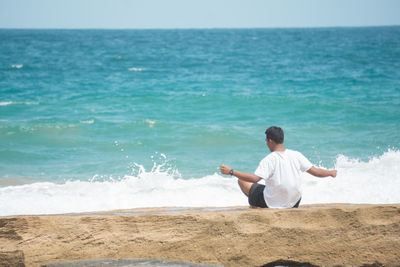 Rear view of man sitting at beach