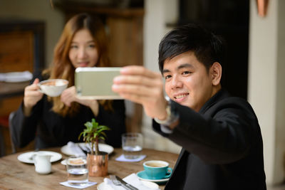 Portrait of woman using phone while sitting on table