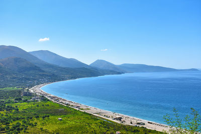 Scenic view of sea and mountains against blue sky